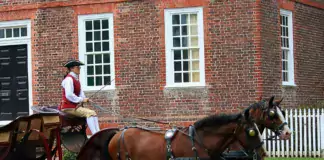 Pferde ziehen eine Kutsche vor einem Backsteingebäude